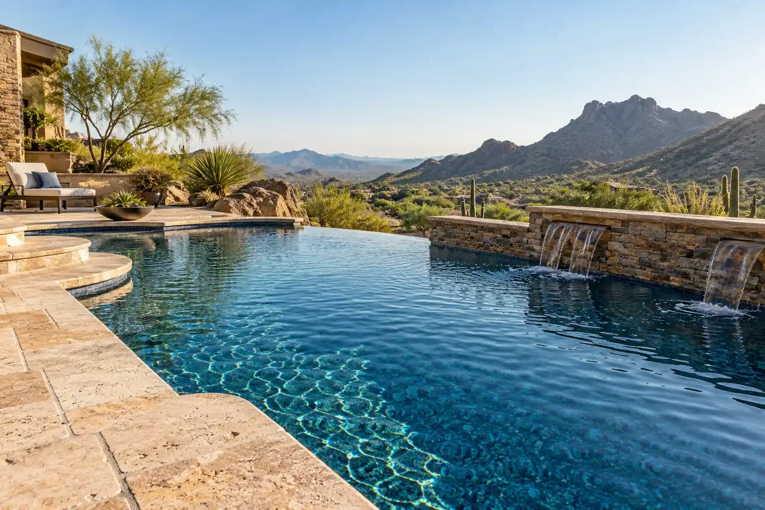 Hillside backyard pool with a dark blue pebble interior, a stacked stone spillway and desert mountains behind
